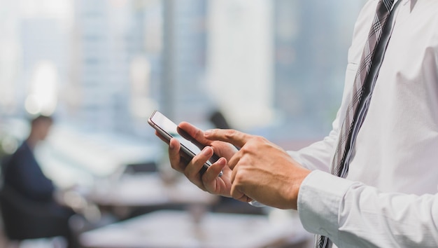 Business man using smart phone in office space background and copy space.