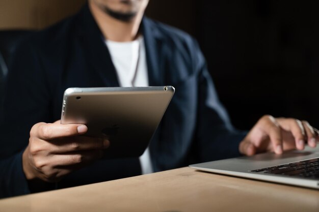 Business man using smart phone, tablet in Dark room. hand holding smart phone.