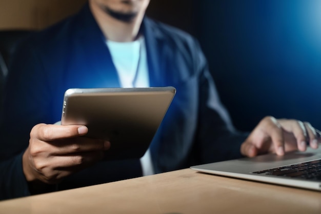 Business man using smart phone, tablet in dark room. hand\
holding tablet.