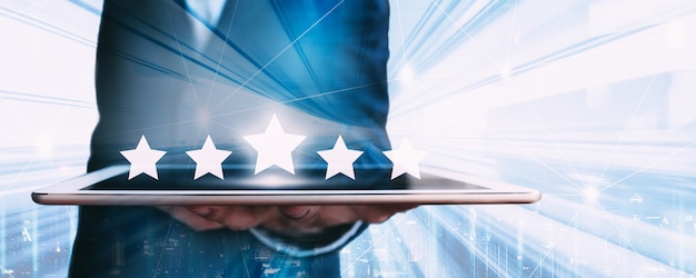 Business man using tablet application with graphic of five star icon to give rate of customer service