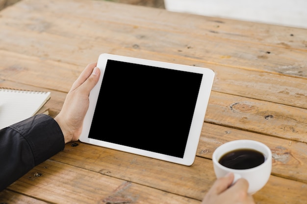 business man using tablet on wood table in coffee shop.