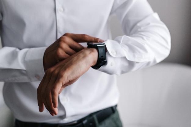 Foto un uomo d'affari in una camicia bianca utilizzando uno smartwatch le mani dell'uomo si chiudono