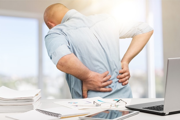 Business man with back pain sin an office . Pain relief concept