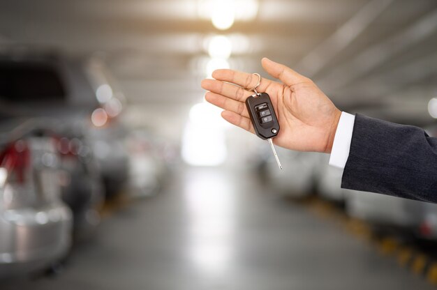 A business man with a car key on the back of a parking lot