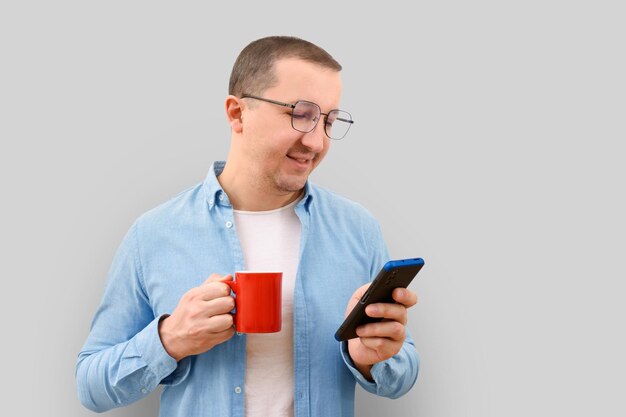 Business man with a cup and a phone in his hands on a gray background