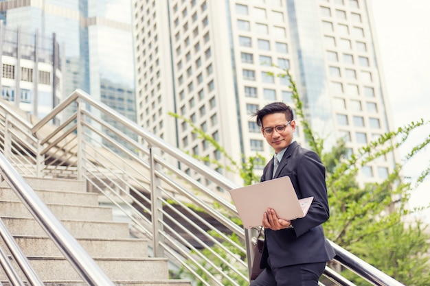 Business man with his laptop going up the stairs  in a rush hour to work 