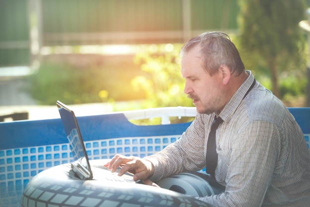 Business man with a laptop working in the pool tinting