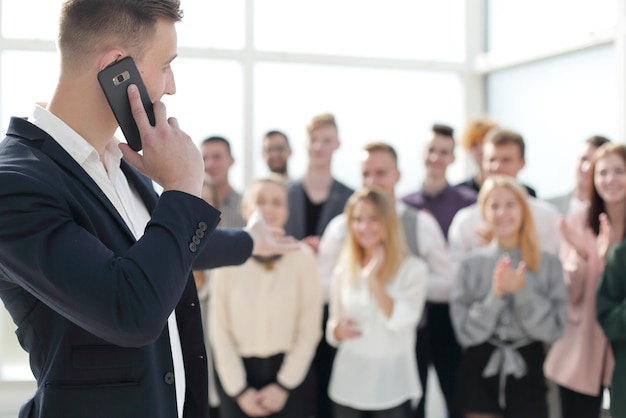 Business man with smartphone pointing at a group of young people