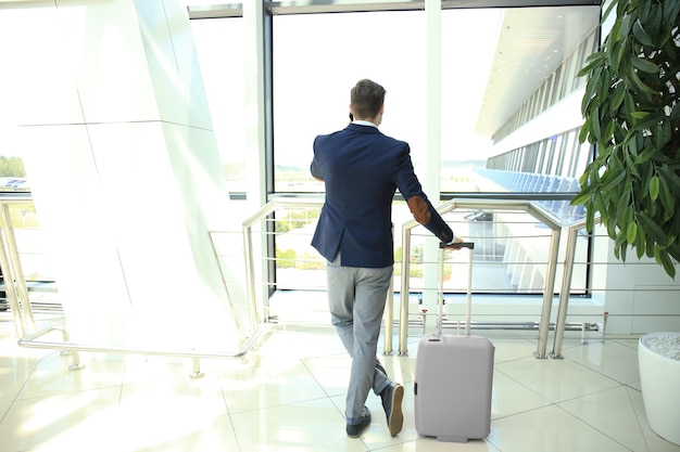 Business man with suitcase in hall of airport.