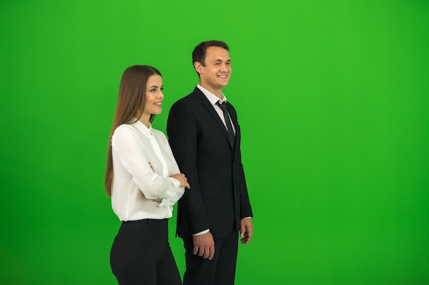 The business man and woman stand on the green background