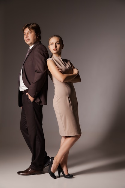 Business man and woman standing back to back  isolated on brown background. Teamwork concept