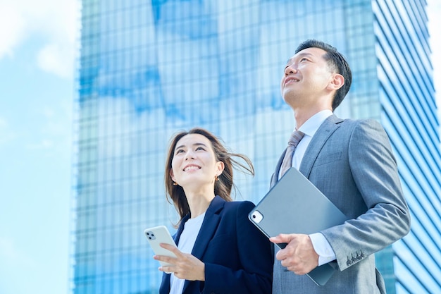 Business man and woman standing in front of skyscraper