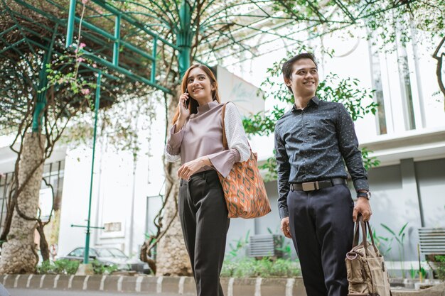 Business man and woman walking trough sidewalk smiling going to office