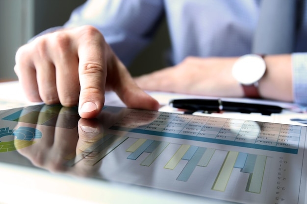 Business man working and analyzing financial figures on a graphs on a tablet