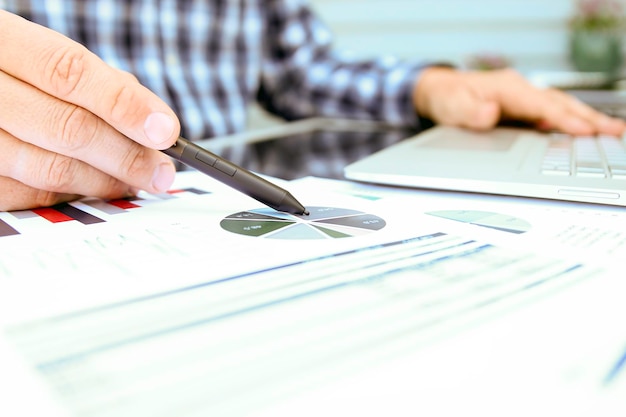 Business man working and analyzing financial figures on a graphs using laptop