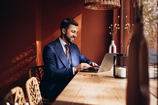 Foto uomo d'affari che lavora su un laptop e beve caffè in una caffetteria