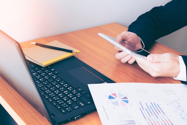 Business man working at office with smart phone and documents on his desk