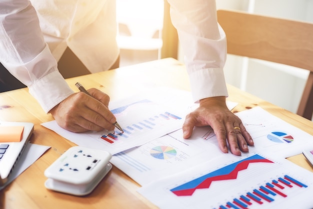 Business man working with analyze graph data document plans at the desk in office.