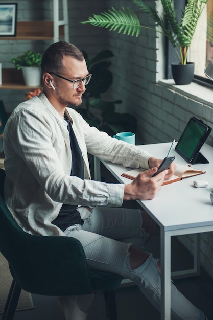 Business man writing on paper notebook on office table during working from home using tablet and mobile phone Business portrait Education concept Distance education