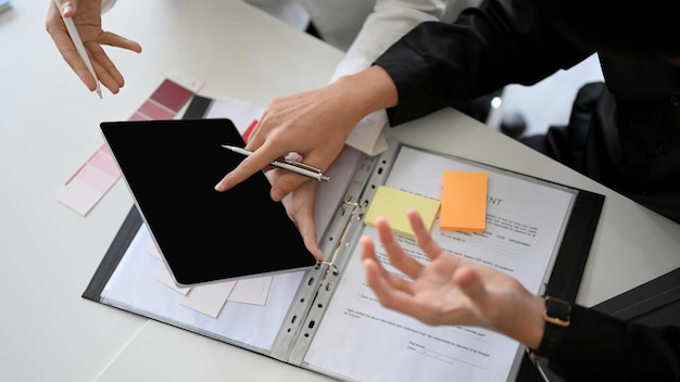 Business management team pointing their finger on tablet black screen over office desk