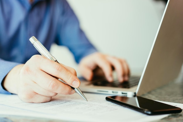 Business manblue shirt sitting at his working place in office holding a pen