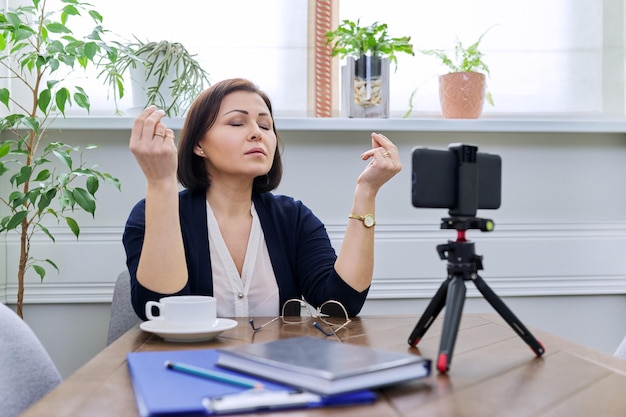 Business mature woman meditating at home workplace in between online work