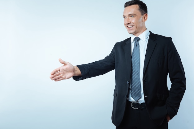 Business meeting. Joyful delighted positive man giving his hand and smiling while having a business meeting