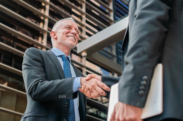 Photo business men shaking hands for strike a deal white collar workers smiling and having a collaboration