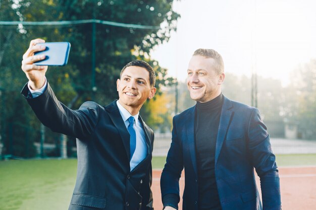 Photo business men taking selfie on a tennis court