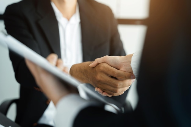 Business men and women shake hands confidently at an office\
meeting