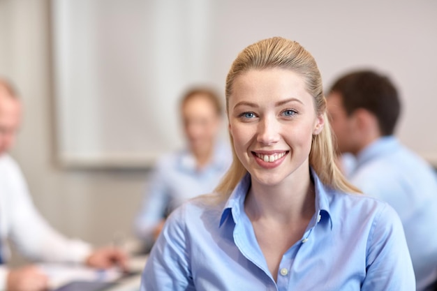 business, mensen en teamwork concept - glimlachende zakenvrouw met een groep zakenmensen die op kantoor bijeenkomen