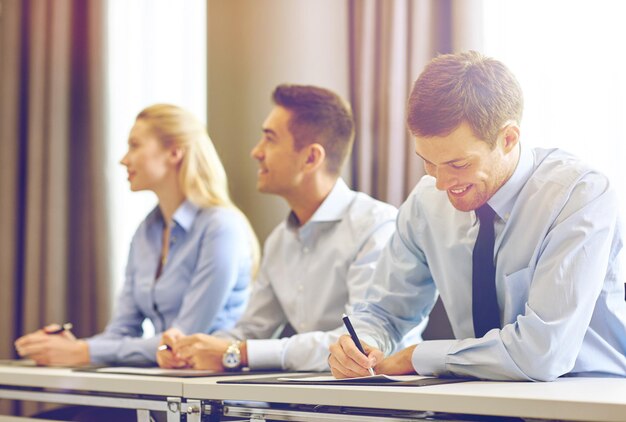 business, mensen en teamwork concept - groep lachende zakenmensen ontmoeten elkaar op presentatie in office