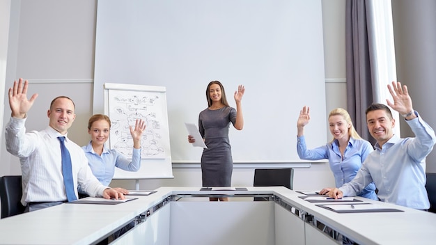 business, mensen en teamwork concept - groep lachende zakenmensen ontmoeten en zwaaien handen in office