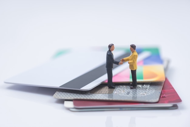 business miniature people shaking hands on credit card stack background