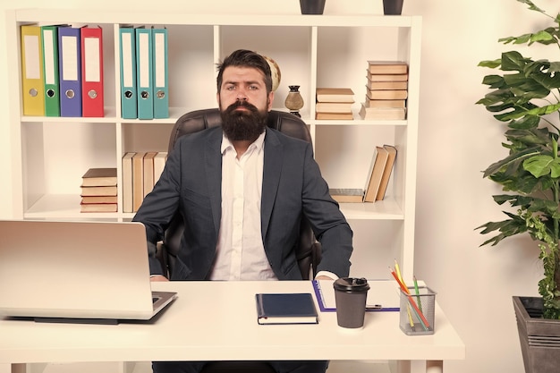 Business Modern businessman Bearded man Mature hipster with beard Male fashion in business office Confident brutal man Businessman in formal suit Man Portrait of man sitting at desk in office