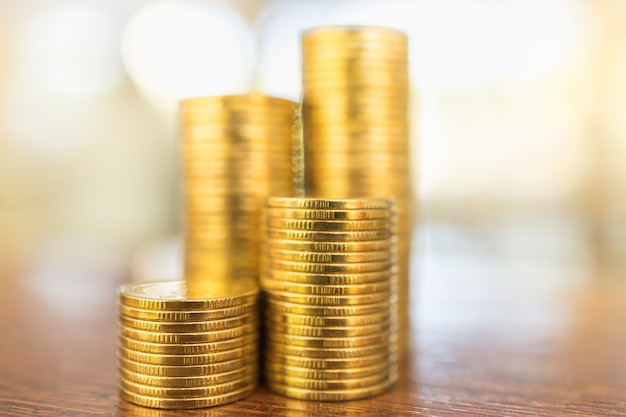 Business, Money, Finance, Security and Saving Concept. Close up of stack of gold coins on wooden table under sunlight with copy space.