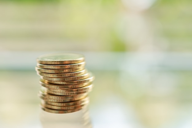 Business, Money, Finance, Security and Saving Concept. Close up of unstable stack of gold coins on table with green nature and copy space.