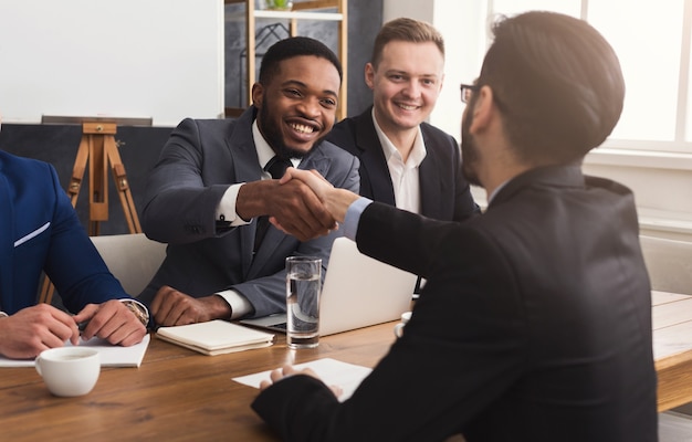 Business multiethnic handshake at office corporate meeting, contract conclusion and successful agreement concept. Modern businessman and other man's hands meet