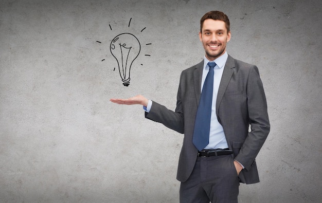 business, office, advertising and people concept - friendly young buisnessman showing light bulb on the palm of his hand