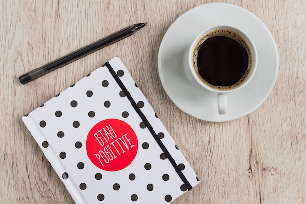 Business and office concept - black and white polka dot cover notebook, smartphone and cup of black coffee on wooden table. top view.