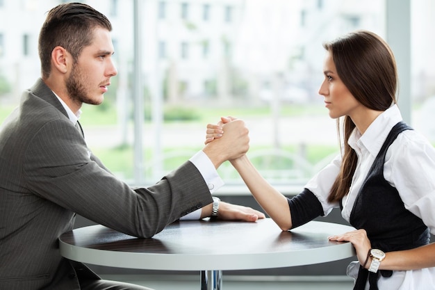 Photo business and office concept businesswoman and businessman arm wrestling during meeting in office