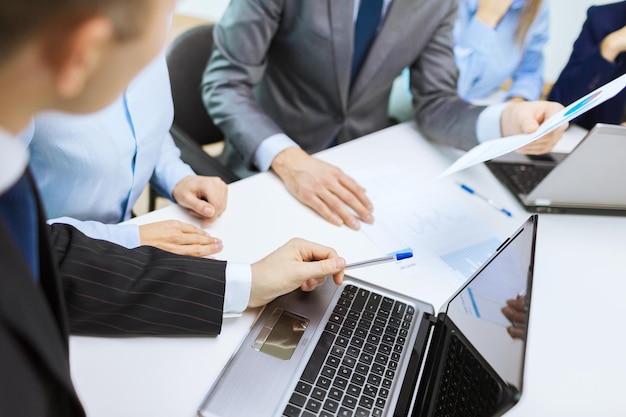 business and office concept - close up of business team with files and laptop computer in office