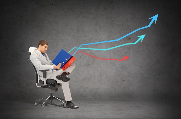 business and office concept - handsome businessman in suit with folders sitting on chair