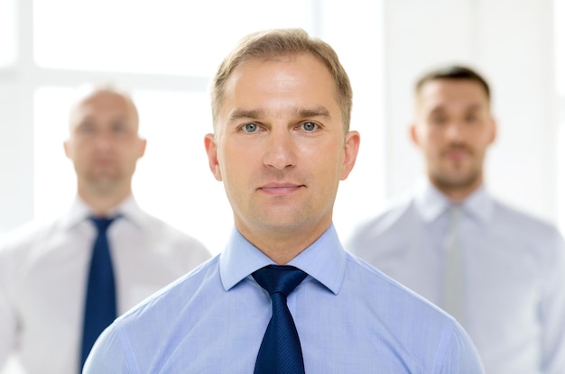 business and office concept - serious businessman in office with team on the back