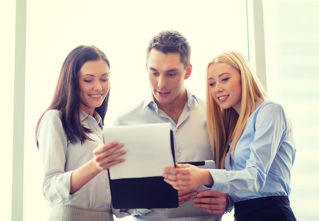 business and office concept - smiling business team looking at clipboard