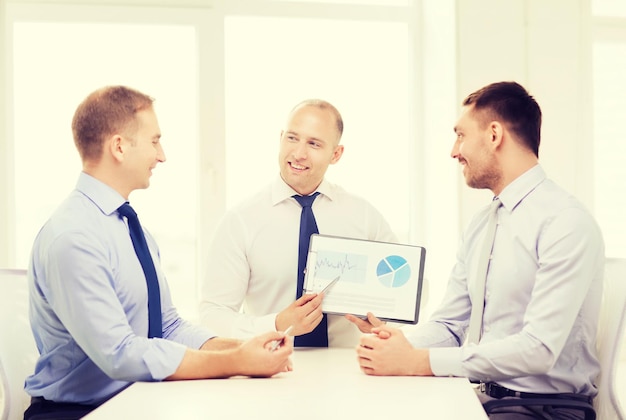 business and office concept - smiling businessman showing others charts in office