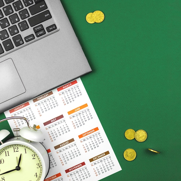 Фото Деловой офисный стол с ноутбуком и календарем с деньгами, золотыми монетами, фото концепции времени - деньги