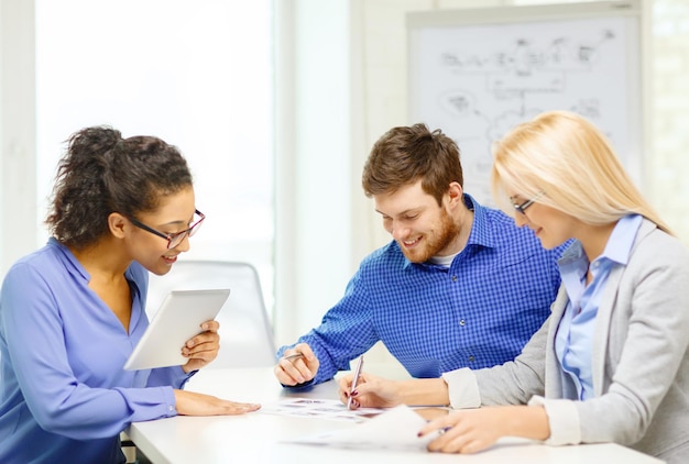 business, office en startup concep - glimlachend creatief team met tafel-pc-computers en papieren die op kantoor werken