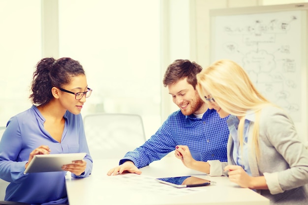 business, office en startup concep - glimlachend creatief team met tafel-pc-computers en papieren die op kantoor werken