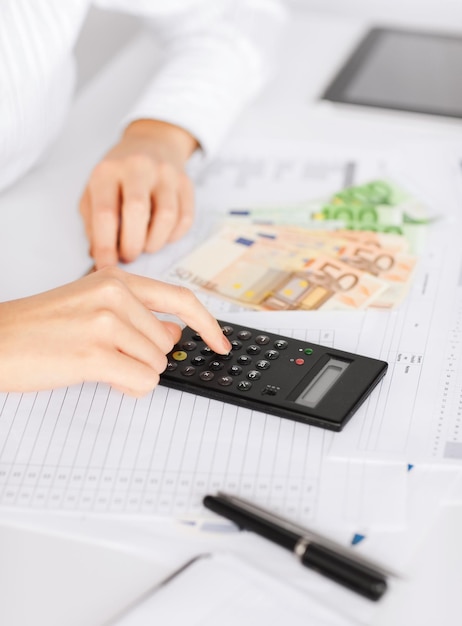 business, office, household, school, tax and education concept - woman hand with calculator and euro money